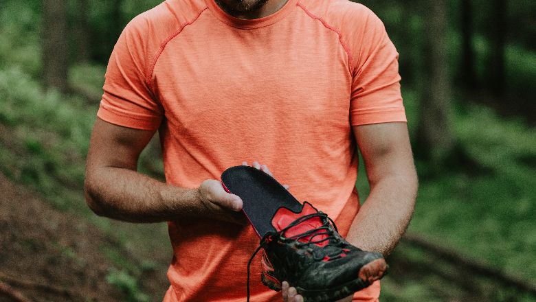 Person In An Orange Shirt Holding An Orthotic For Fall Hiking Season